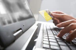 Image of hands holding credit card and pressing a keys of keyboard