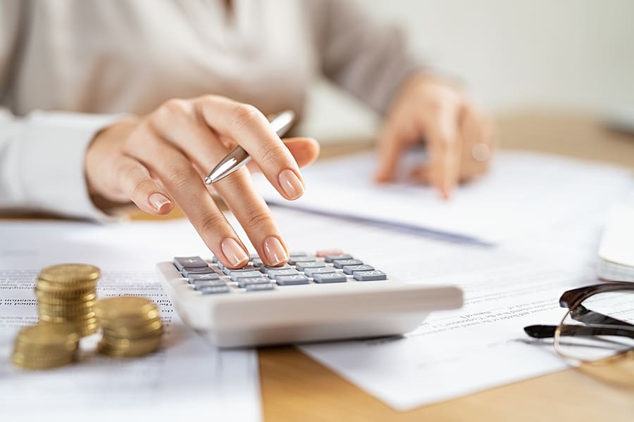 Woman using a calculator doing a balance of monthly expenses.