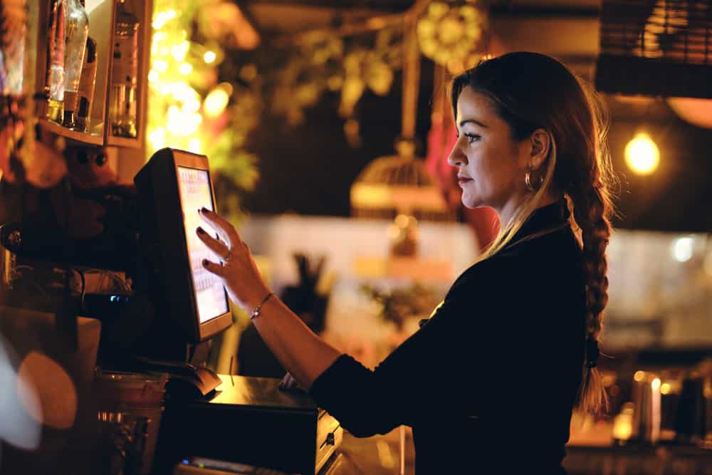 A lady works at a point of sale system in a restaurant. 